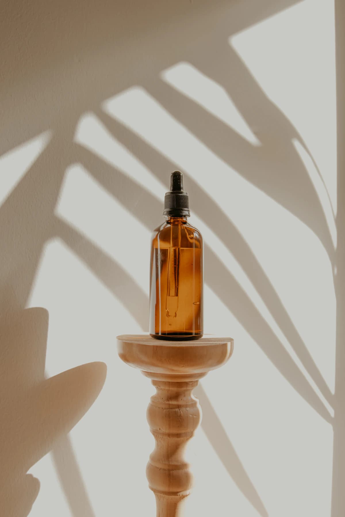 Un flacon ambré sur un socle, dans une lumière de soleil